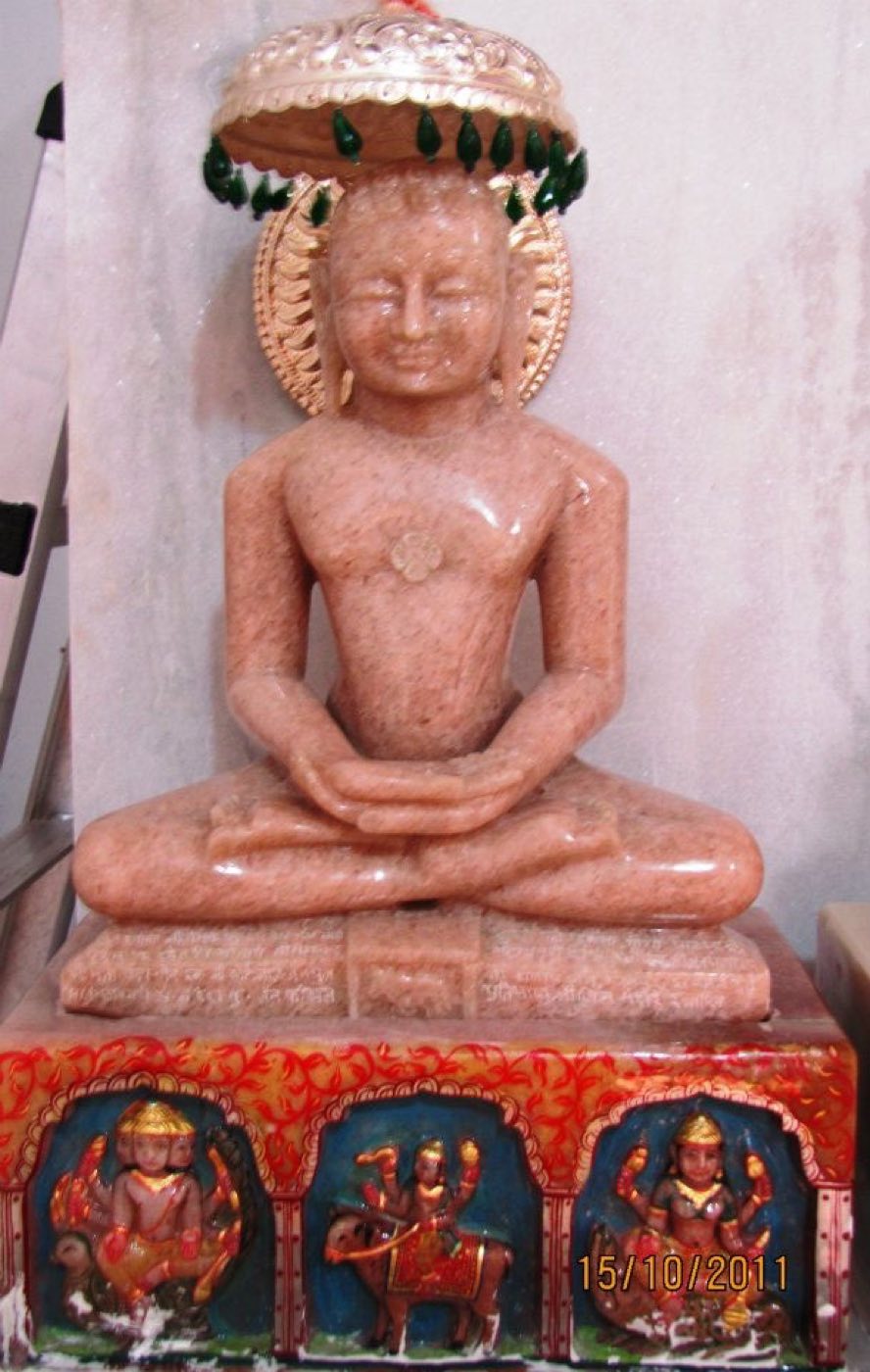 Pink-stone pratima of a Tirthankara beneath a chhatra at the mandir