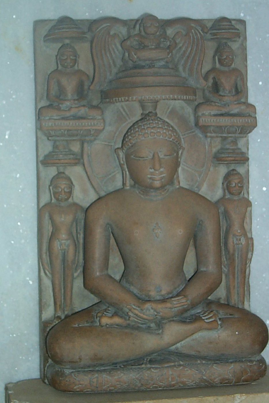 Stone relief of a Tirthankara seated in dhyan with attendant figures